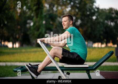 Schöner mann Training im Fitnessbereich im Freien auf Übung Ausrüstung Stockfoto