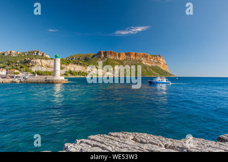 Stehend auf dem felsigen Ufer mit Blick auf ein kleines Boot in den Hafen von Cassis. Stockfoto