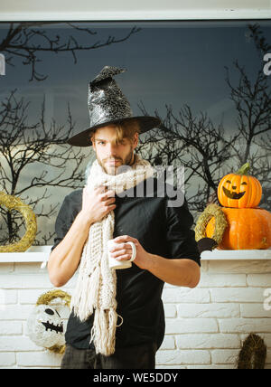 Halloween Mann hält Schale am Fenster mit Bäume im Herbst Stockfoto