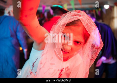 Kleines Mädchen Halten der Kamera in einem jäten Kleid in Blut für Halloween Karneval abgedeckt gekleidet. Creepy girl. Stockfoto