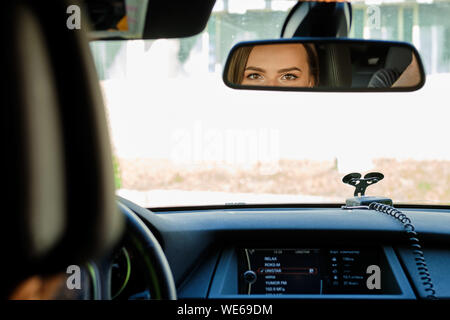 Reflexion der weiblichen Augen im Rückspiegel eines Autos Stockfoto