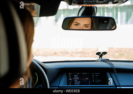 Reflexion der weiblichen Augen im Rückspiegel eines Autos Stockfoto