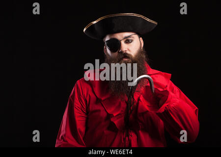 Portrait von gut aussehenden bärtigen Mann mit mittelalterlichen pirate Kleidung für Halloween Karneval. Mann in Piraten Kostüm über schwarzen Hintergrund. Stockfoto