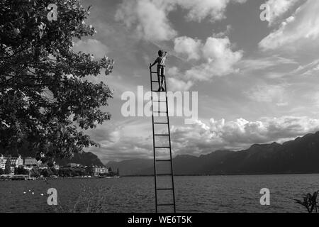 Schwarz-weiß Bild von seeseite Statue des Jungen klettern eine Leiter Stockfoto