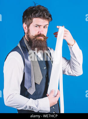 Auf der Suche nach etwas anderes als eine klassische Krawatte. Fashionist oder Hipster. Bärtige hipster Holding weißer Seide Krawatte. Brutale Hipster mit Krawatte Kollektion. Kaukasische Hipster mit modischen Accessoires. Stockfoto