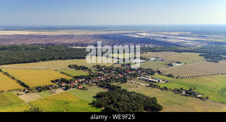 23. August 2019, Brandenburg, Welzow: Das kleine Dorf Proschim im südlichen Brandenburg mit der Braunkohle Tagebau Welzow Süd der Lausitz Energie Bergbau AG (Leag) Dahinter (Luftaufnahme aus einem Flugzeug). Proschim ist möglicherweise für die Welzow Süd brown Coal Mine ausgegraben werden. Anwohner und Umweltverbände haben, verteidigt sich gegen diese schon seit vielen Jahren. Foto: Patrick Pleul/dpa-Zentralbild/ZB Stockfoto
