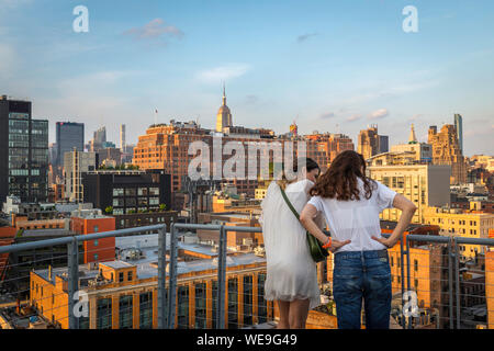 Chelsea New York, Ansicht von hinten im Sommer von zwei Frauen, die Freunde, die an Gebäuden im Chelsea Gegend von Downtown Manhattan, New York City, USA Stockfoto