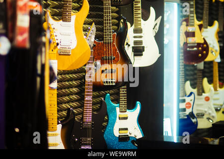 Gitarren in verschiedenen Farben im Music Store. Bunte E-Gitarren hängen an der Wand, Musik instrumente. Rock und Roll, Musik, professionelle, Shop, Stockfoto