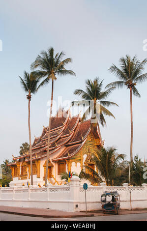 Luang Prabang, Laos - Luang Prabang Royal Palace Museum und Hor Prabang Temple Hall unter der Kokospalme mit Tuk Tuk Park an der Wand Seite und Morgen quie Stockfoto