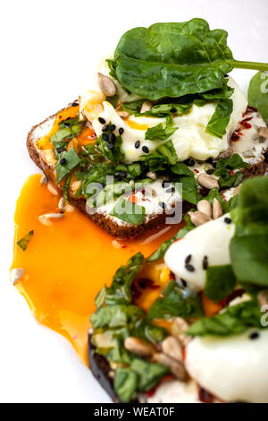 Sandwiches mit pochierten Eiern, Käse, Spinatblätter, Sesamsamen und Samen. Gesundes Frühstück oder einen Snack auf dem weißen Hintergrund Stockfoto