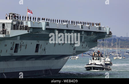 Mitgliedern der Besatzung stehen auf Deck als HMS Queen Elizabeth segeln von Portsmouth Naval Base setzt, für den Einsatz in die Vereinigten Staaten. Stockfoto