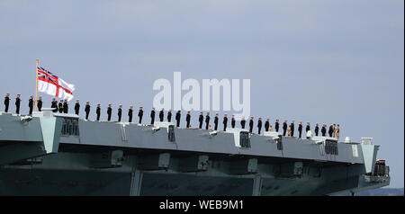 Mitgliedern der Besatzung stehen auf Deck als HMS Queen Elizabeth segeln von Portsmouth Naval Base setzt, für den Einsatz in die Vereinigten Staaten. Stockfoto