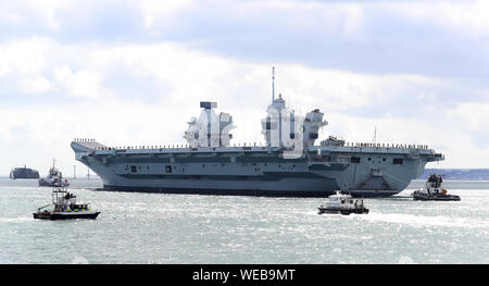 Mitgliedern der Besatzung stehen auf Deck als HMS Queen Elizabeth segeln von Portsmouth Naval Base setzt, für den Einsatz in die Vereinigten Staaten. Stockfoto