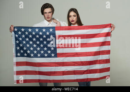 Paar auf ruhige Flächen hält Flagge der USA. Paar begrüßt die USA zu besuchen. Guy und Mädchen stolz, Amerikaner zu sein, grauen Hintergrund. Language School Konzept Stockfoto