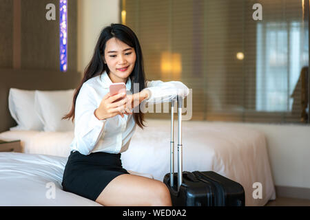 Asiatische Frau am Telefon, im Hotel Zimmer. Führungskraft auf Geschäft Tour am Telefon sprechen von Hotel Zimmer. Stockfoto