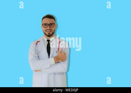 Positiv denkenden Praktiker mit Daumen nach oben posiert mit blauen Hintergrund. Stockfoto