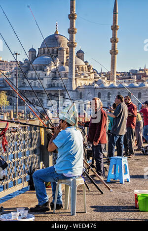 Istanbul, Türkei - 16 April, 2016 - Männer zu sozialisieren, wie sie Fische von einer Brücke mit der Blauen Moschee im Hintergrund Stockfoto