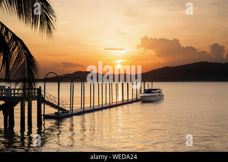 Speed Boot auf dem schwimmenden Pier mit Sonnenuntergang im Hintergrund. Stockfoto