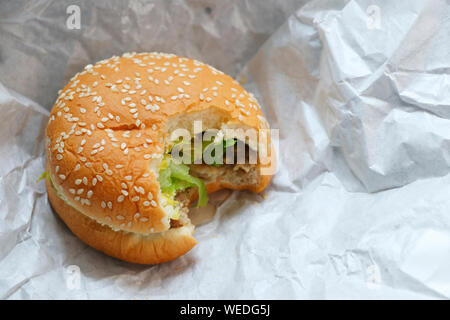 Hamburger mit bissspuren auf weißem Papier. Stockfoto