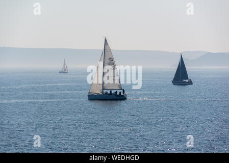 Segelboote vor der Küste von Scarborough, North Yorkshire, Großbritannien, in einer ruhigen, dunstiger Sommermorgen. Stockfoto