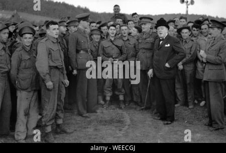 Churchill begleitet den Gesang bei einem Besuch in einem australischen Militärlager. Duncan Sandys in Offiziersuniform auf der linken Seite der Fotografie.9. September 1940 Stockfoto