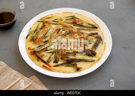 Hausgemachte koreanischen Pajeon Schalotten Pfannkuchen auf einer weißen Platte auf einem grauen Hintergrund, Seitenansicht. Asiatische Küche. Stockfoto