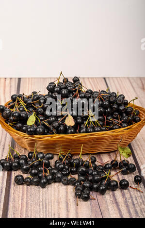 Reif Aronia Beeren in einem Weidenkorb auf dem Tisch. Stockfoto