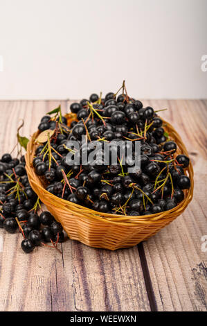 Reif Aronia Beeren in einem Weidenkorb auf dem Tisch. Stockfoto