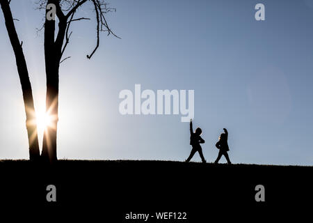 Kleinkinder spielen auf einem Hügel mit der Sonne hinter Ihnen - auffallend eine Macht darstellen, Stockfoto