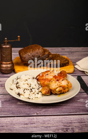 Hähnchenschenkel mit Gewürzen gebraten in einen Kessel, serviert auf einem Teller mit Reis. Stockfoto