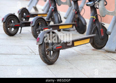 Elektroroller auf einer Straße in einem sonnigen Tag geparkt. Umweltfreundliche Verkehrsmittel, e-Scooter auf Parkplatz Stockfoto