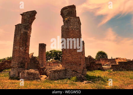 Sonnenuntergang bei archäologischen Ausgrabungen von Ostia Antica mit dem Wahrzeichen von der Therme von Marine Tür in Italienisch "Porta Marina" ruinieren. Stockfoto