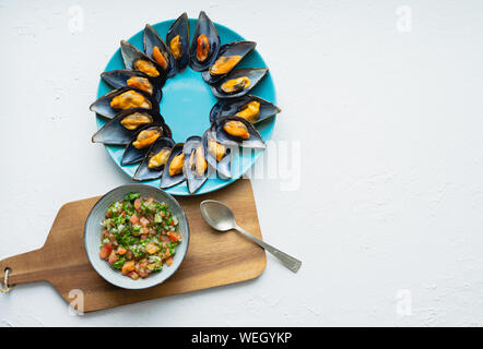 Gedämpfte Muscheln mit Zwiebel, Tomate und Koriander vinaigrette auf weißem Hintergrund und Küche. Kopieren Sie Platz. Ansicht von oben. Stockfoto