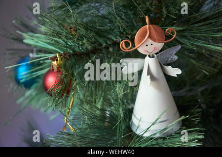 Lächelnde Engel Abbildung auf Weihnachtsbaum mit zwei Weihnachten Kugeln aus Fokus in den Hintergrund. Stockfoto