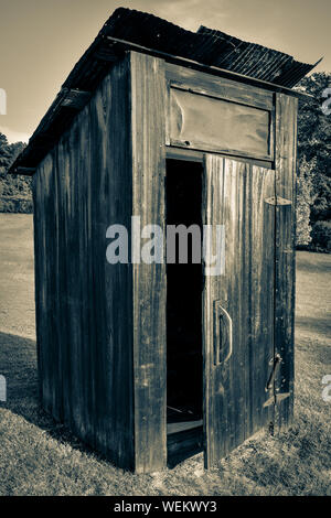 Alte, Verwitterte heraus - Haus oder Toilette, mit Tür offen mit rostigen Dach auf einem Hügel mit Bäumen im Südosten der USA Stockfoto