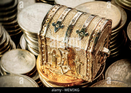 Kleine gold metall Schatztruhe über überdimensionale Münze Stapel Stockfoto