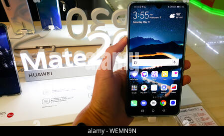 BANGKOK, THAILAND - 11. MAI 2019: Hände auf Huawei Hassen 20 Serie, willkommen und verfügt über Bildschirm des Smartphones im Einzelhandel shop in Ban zeigen Stockfoto