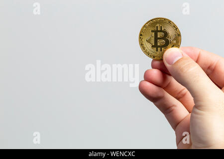 Mann hand mit einem physischen bitcoin vor einem weißen Hintergrund Stockfoto