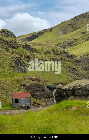 Pjódvegur alte einsame kleine Haus saß auf dem Fuß eines Berges, neben einem kleinen Wasserfall, Island Stockfoto