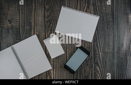 Leeres Papier, Notepad und Notebook mit Handy auf hölzernen Schreibtisch flach zurück zu Schule Konzept Stockfoto