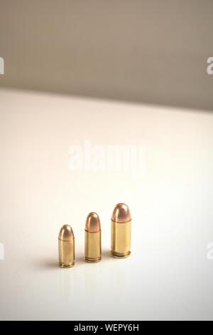 Drei Kugeln verschiedener Kaliber auf eine weiße Fläche. Von links nach rechts: .380 Auto FMJ 9 x 19 mm FMJ .45 Auto FMJ links Stockfoto