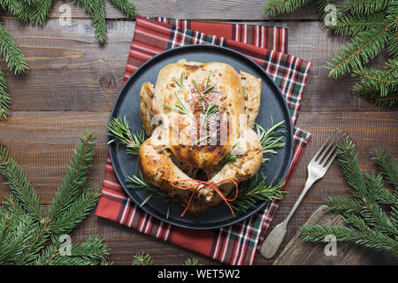 Traditionelle Weihnachten gebratener Truthahn mit Gewürzen und Rosmarin auf Holztisch mit Dekor der immergrünen Zweigen. Ansicht von oben. Platz für Text. Weihnachten. Stockfoto