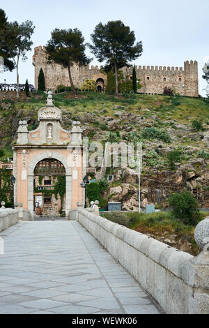 TOLEDO, Spanien - 24 April 2018: Ausblick auf die barocke Triumphbogen auf der Alcantara Brücke über den Fluss Tejo und die Burg in San Servando Toledo. Stockfoto