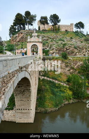 TOLEDO, Spanien - 24 April 2018: Ausblick auf die barocke Triumphbogen auf der Alcantara Brücke über den Fluss Tejo und die Burg in San Servando Toledo. Stockfoto