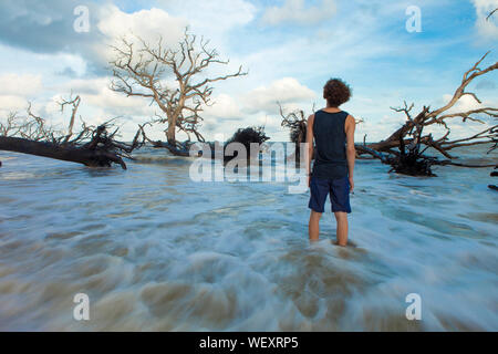 Die langzeitbelichtung junger Mann in fließendes Wasser auf der Suche nach Toten überschwemmten Bäume Stockfoto