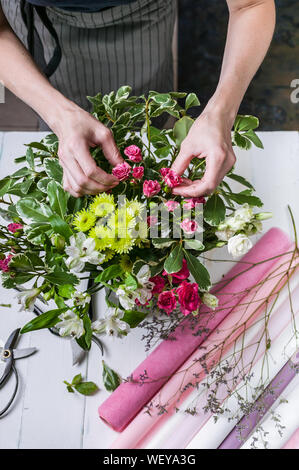 Florist im Werk. Frauenhände, eine Hochzeit Strauß Rosen. Small Business Konzept. Vertikaler Dampfstoß Stockfoto