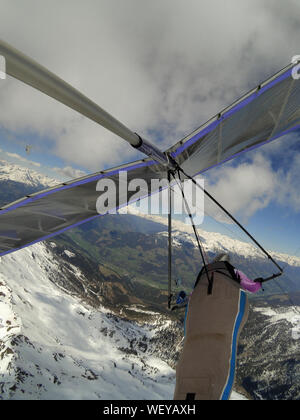 Mutige Drachenflieger Piloten fliegen auf Höhe über Berg mit Schnee bedeckt. Extreme Antenne Sport. Drachenfliegen Stockfoto