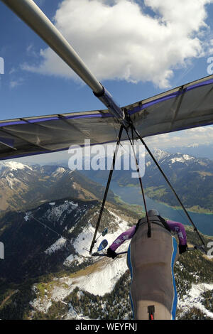 Hängegleiter Pilot fliegt über Berge mit Schnee, Gipfel und blauen Seen in den Tälern bedeckt. Extreme Sport in Greifenburg, Österreich Stockfoto