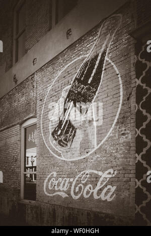 Eine alte Vintage Werbung für Coca-Cola ist Fading auf einer alten Mauer eines Gebäudes in downtwown Tupelo, Mississippi, USA, in Sepia Stockfoto