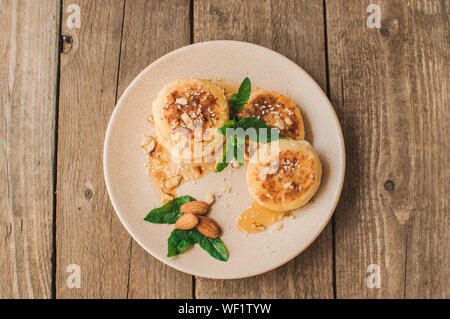 Köstliches Frühstück - Quark Pfannkuchen, Käsekuchen, Quark Pfannkuchen mit Mandeln, Minze und Ahornsirup in beige Platte. Nützliche Dessert Stockfoto